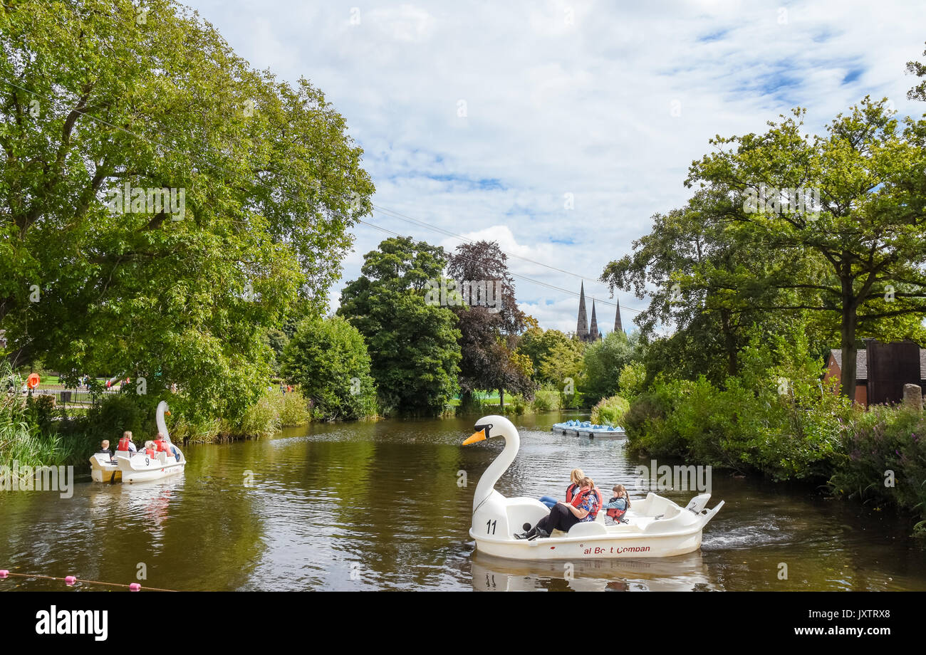Lichfeld Kathedrale von Beacon Park, Lichfield, Staffordshire, Großbritannien gesehen. Personen, die einen warmen Sommertag auf dem Feilbieten Boote am Beacon Park. Stockfoto