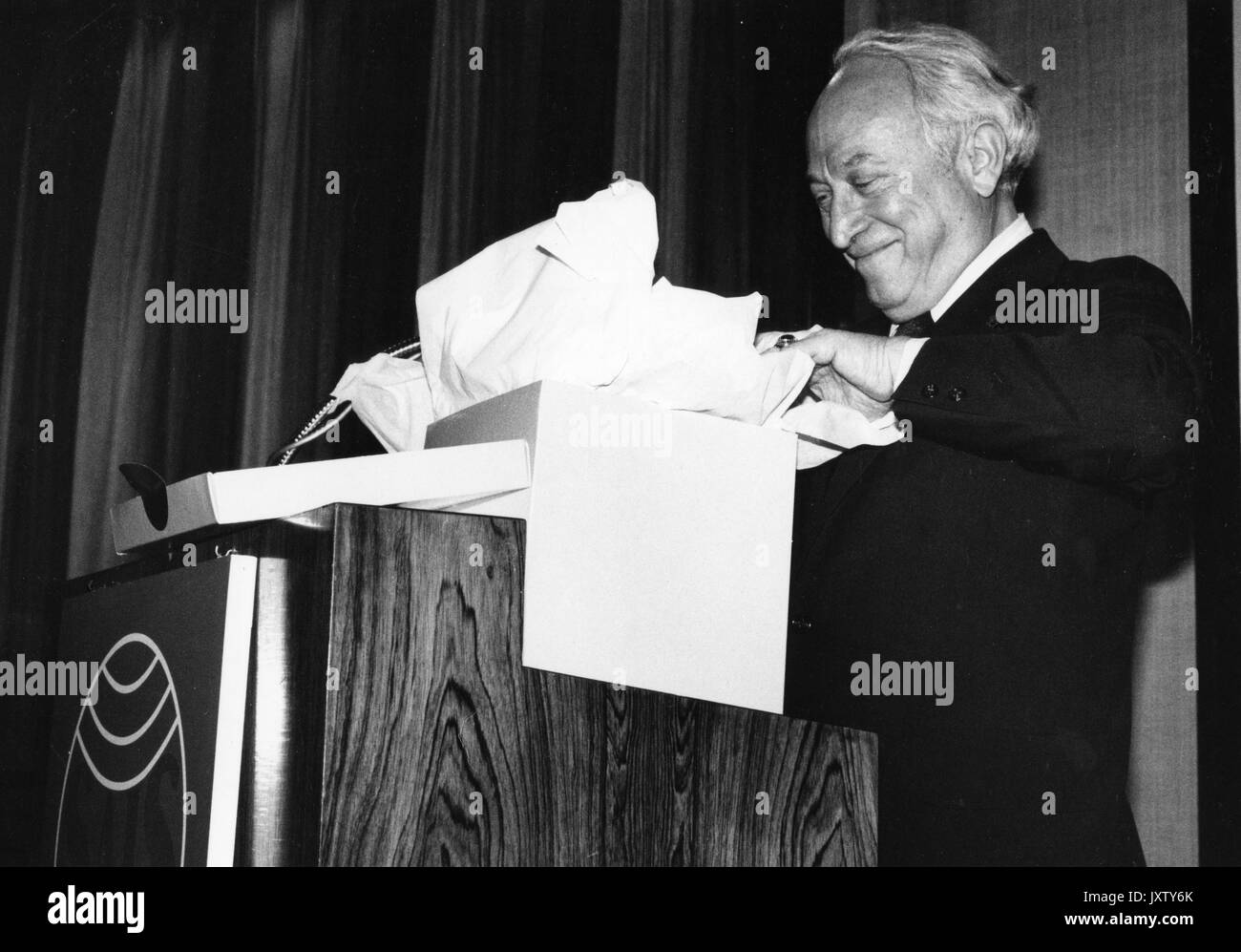 Benjamin Theodore Rome, stehend und öffnet eine Geschenkbox auf einem Podium, 1988. Stockfoto