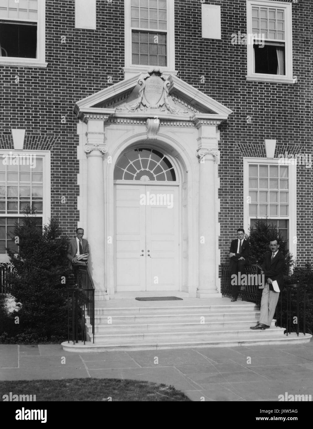 Drei Studenten in Anzügen entspannen sich auf den Stufen der Alumni Memorial Residences an der Johns Hopkins University, 1930. Stockfoto