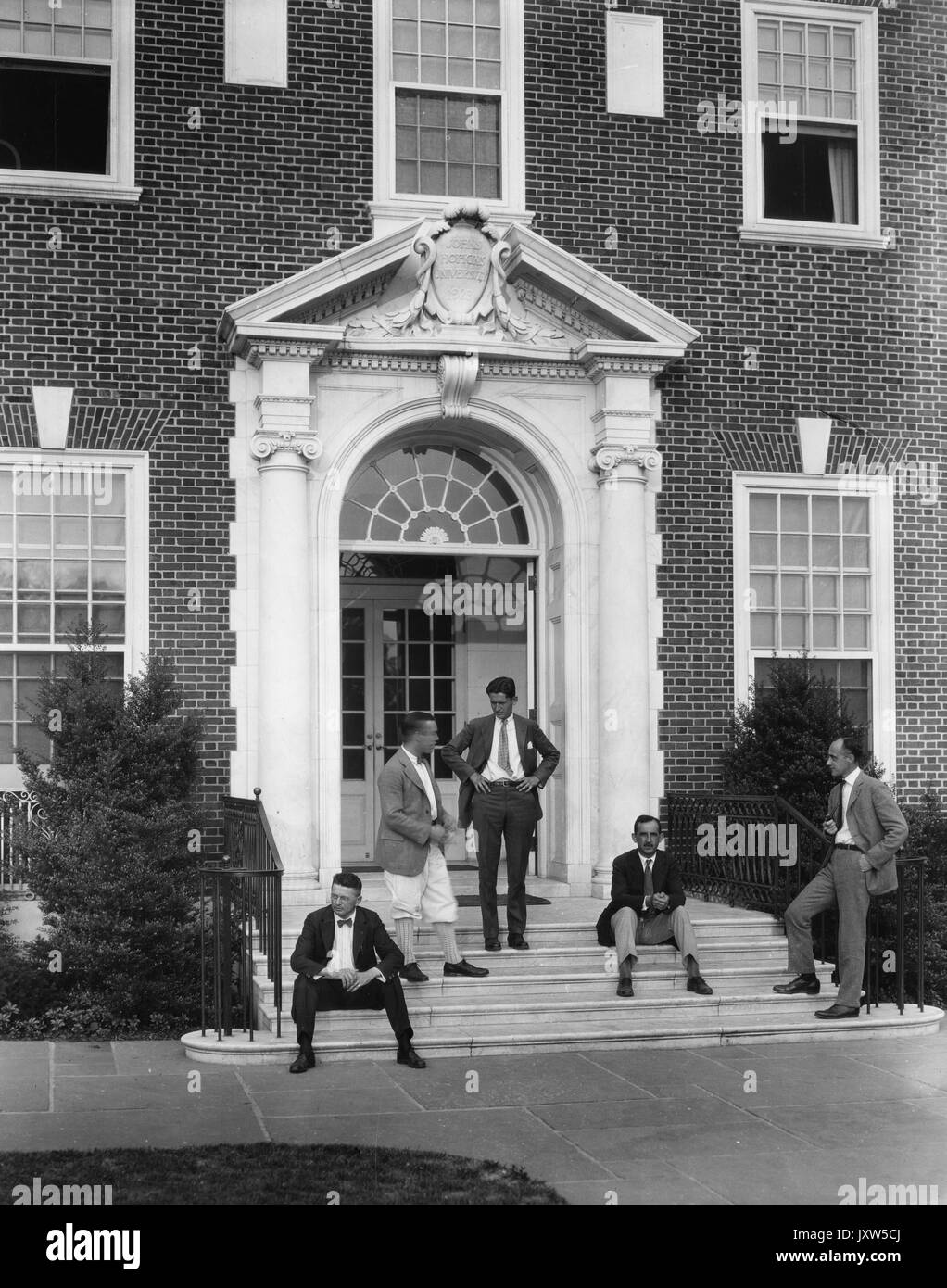 Gruppe von gut gekleideten Studenten, die sich auf den Stufen der Alumni Memorial Residences an der Johns Hopkins University, 1930, entspannen. Stockfoto