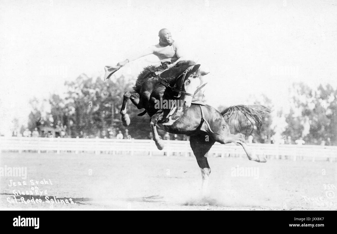 Der afroamerikanische Cowboy Jess Stahl lächelt, als er im California Rodeo Salinas auf dem Pferd Glass Eye reitet, während Zuschauer im Hintergrund zusehen, 1912. Stockfoto