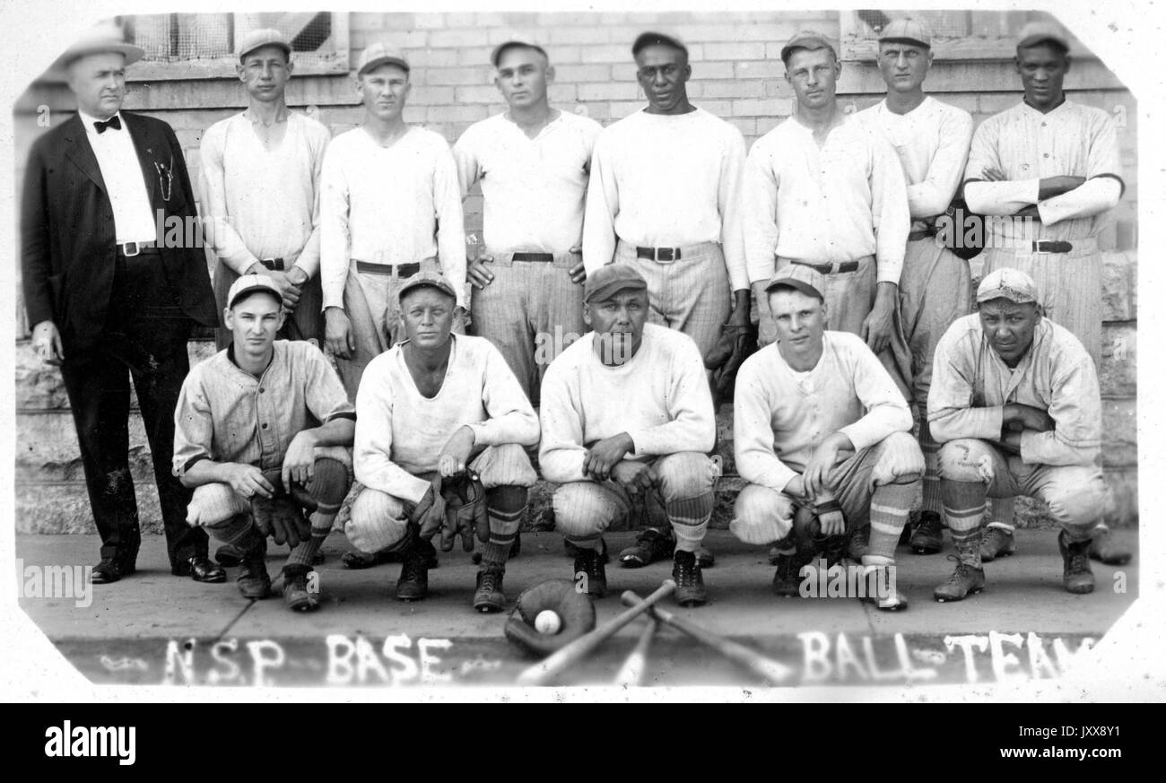 Porträt des Baseballteams der Nebraska State Penitentiary in Uniform, mit drei Fledermäusen, einem Handschuh und einem Ball vor ihnen, deren Trainer links von der Mannschaft steht, Nebraska, 1915. Stockfoto