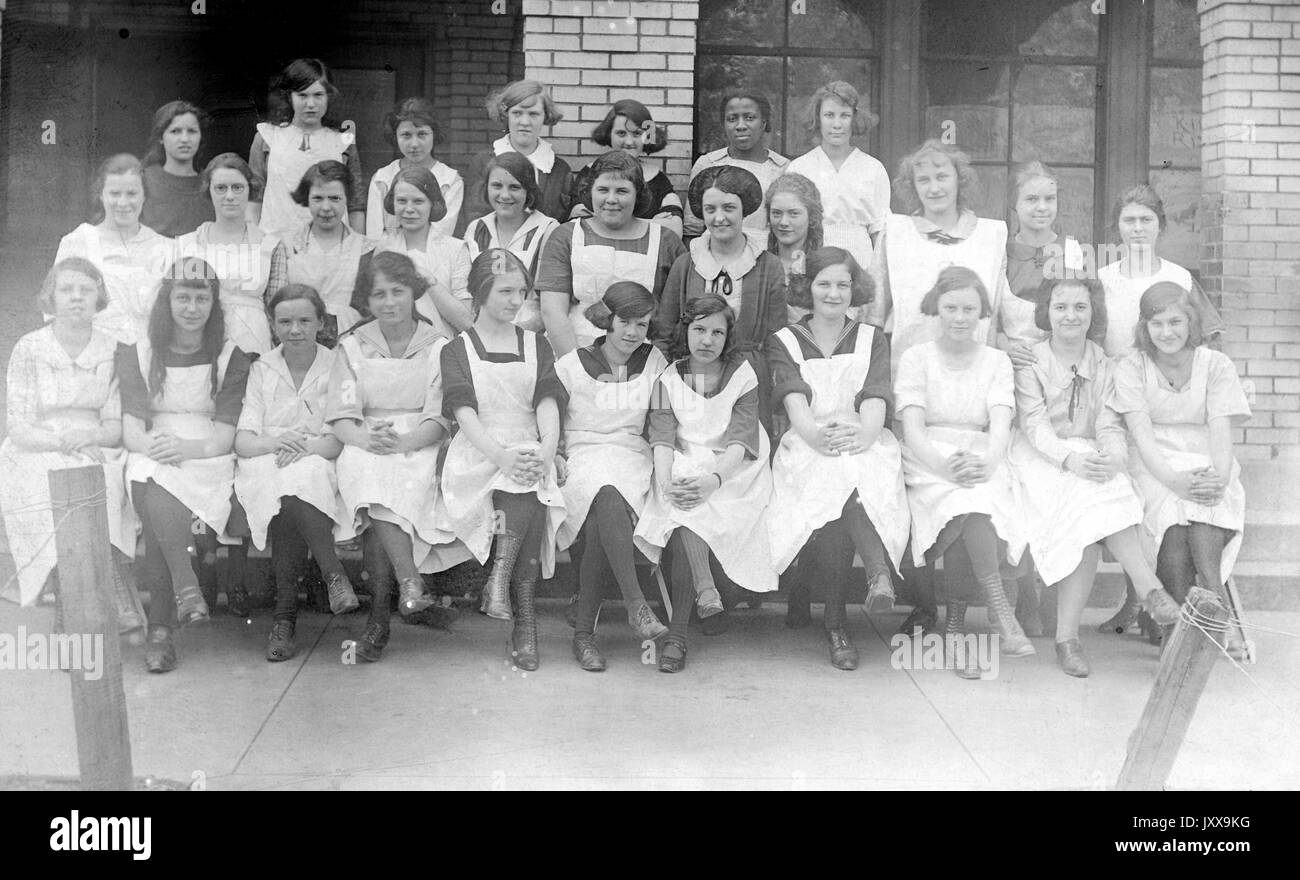 Ganzkörperportrait einer Gruppe von Schülerinnen, erste Reihe sitzend, zweite und dritte Reihe stehend, alle Mädchen in Uniform, lächelnd; ein schwarzes Mädchen in der dritten Reihe, neutraler Gesichtsausdruck; Bridgeport, Ohio, 1920. Stockfoto