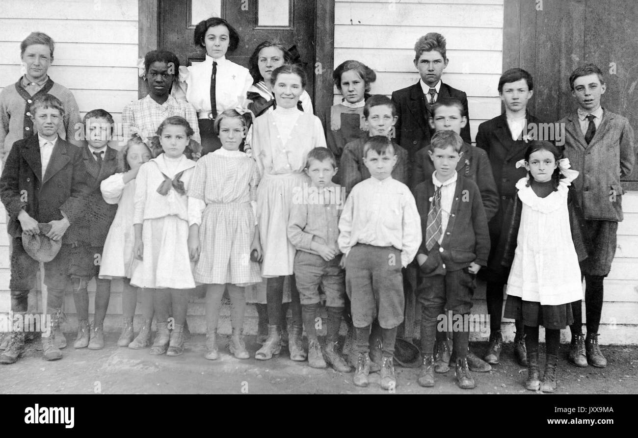 Ganzkörperaufnahme von Schulkindern, stehend außerhalb des Gebäudes, ein afroamerikanischer Student, 1920. Stockfoto