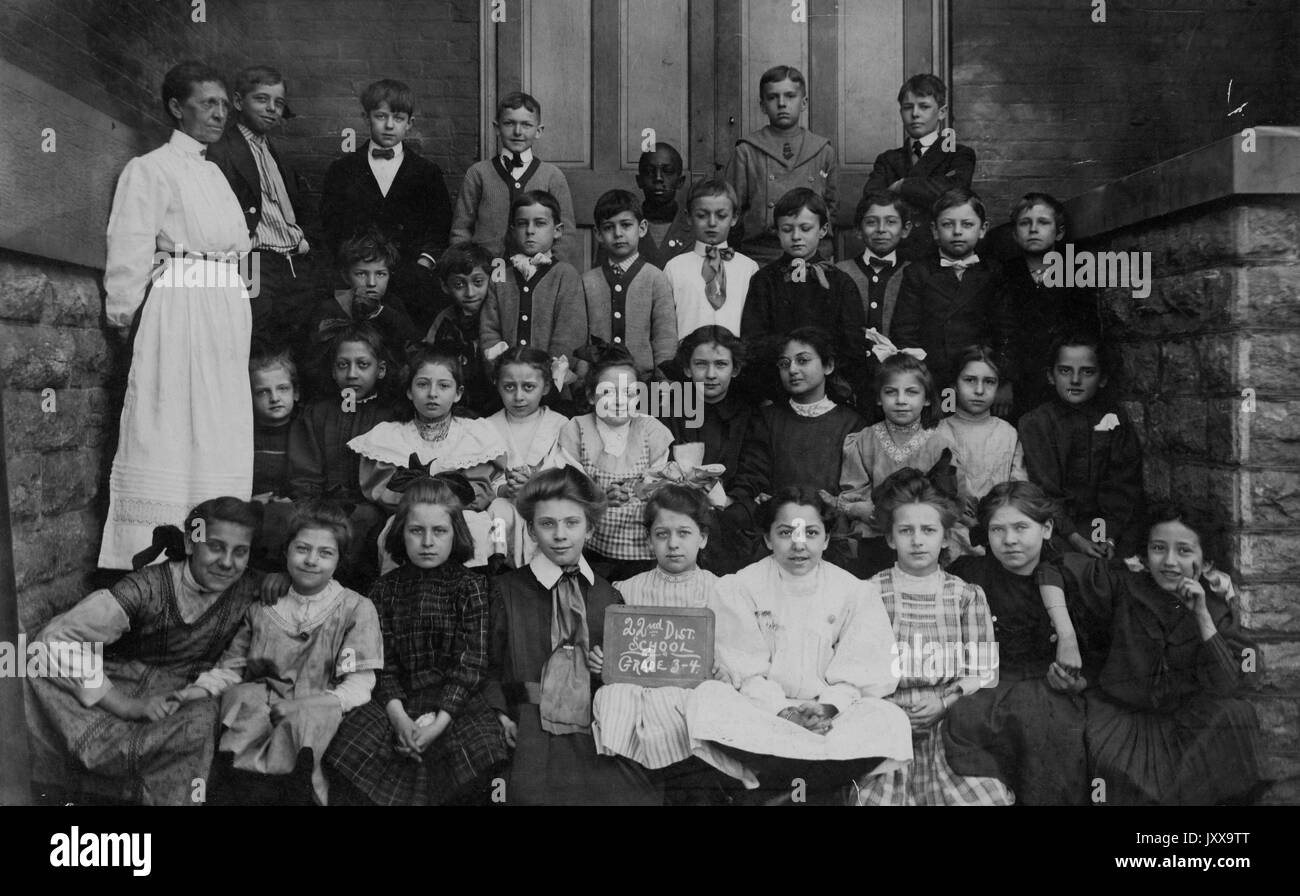 Volle Länge Landschaft schoss der Schulkinder, auf Maßnahmen, die außerhalb von Gebäude sitzt, ein Lehrer; Cincinnati, Ohio, 1920. Stockfoto