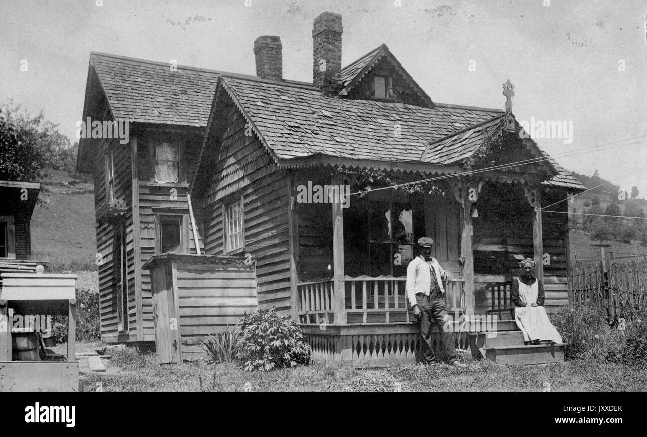 Ein reifes afroamerikanisches Paar sitzt vor der Veranda ihres Hauses in einer ländlichen amerikanischen Stadt, 1915. Stockfoto