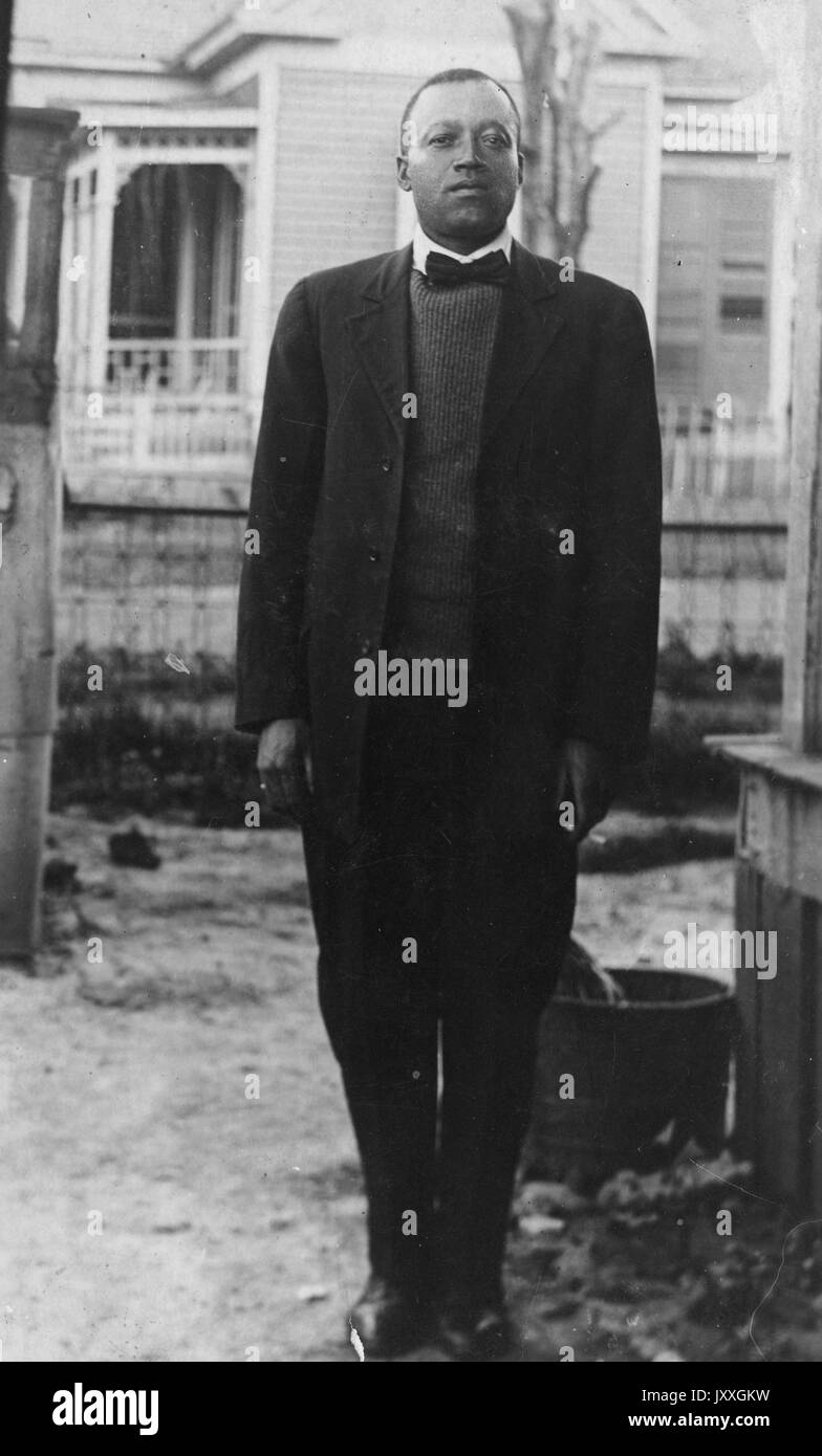 Ganzkörperportrait eines afroamerikanischen Mannes, der Anzug, Füße zusammen, Hände an Seite, im Freien, neutraler Gesichtsausdruck, 1910. Stockfoto