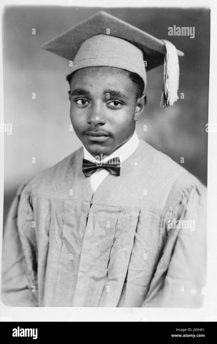 Kopfaufnahme eines jungen afroamerikanischen Mannes, der Abschlusskleid und Hut, Quaste, leichtes Hemd und Fliege trägt, neutraler Ausdruck, 1930. Stockfoto