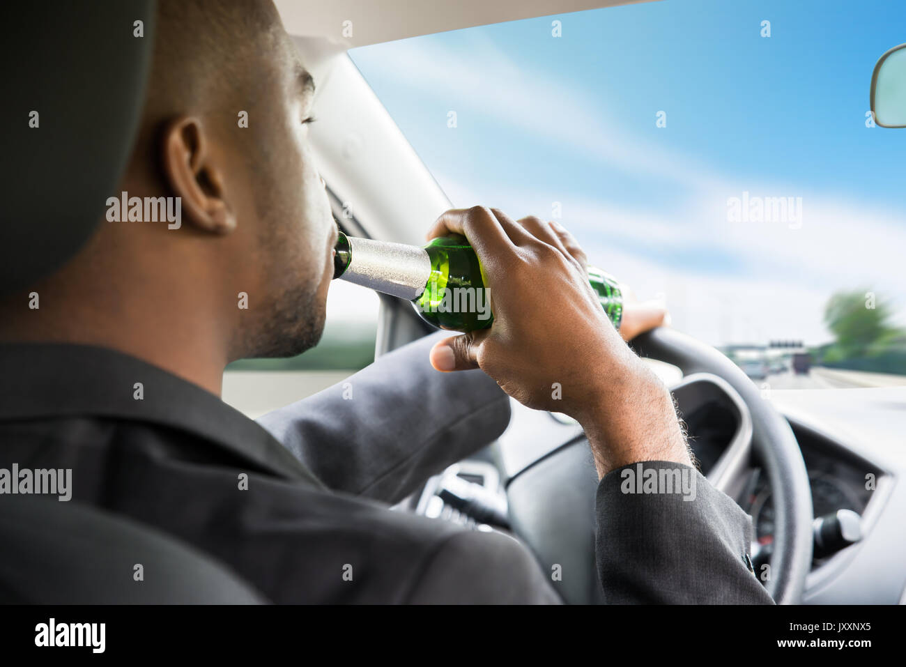 Seitenansicht eines jungen afrikanischen Geschäftsmann Bier trinken während der Fahrt Auto Stockfoto