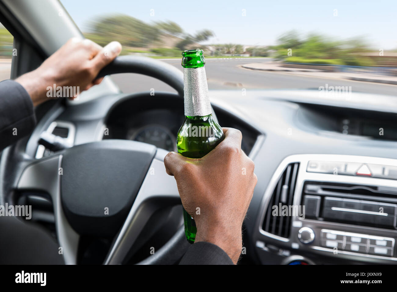 Nahaufnahme einer jungen afrikanischen Geschäftsmann Holding Bier während der Fahrt Auto Stockfoto