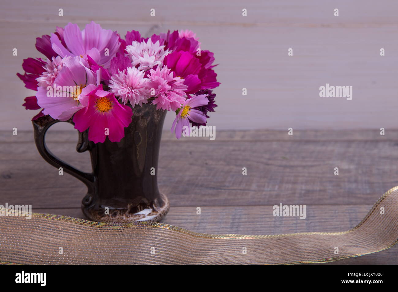 Ein Bouquet von rosa und lila Blumen cosmea oder Cosmos mit Band auf rustikalen hölzernen Brettern. Kopieren Sie Platz. Mutter, Valentines, Frauen, Hochzeit Konzept Stockfoto