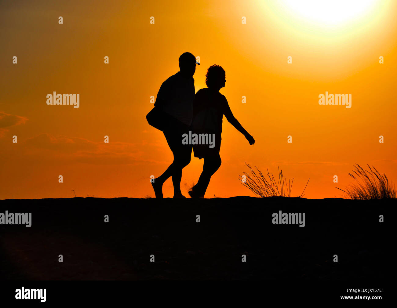 Silhouetten von Menschen, die bei Sonnenuntergang sind zu Fuß Stockfoto