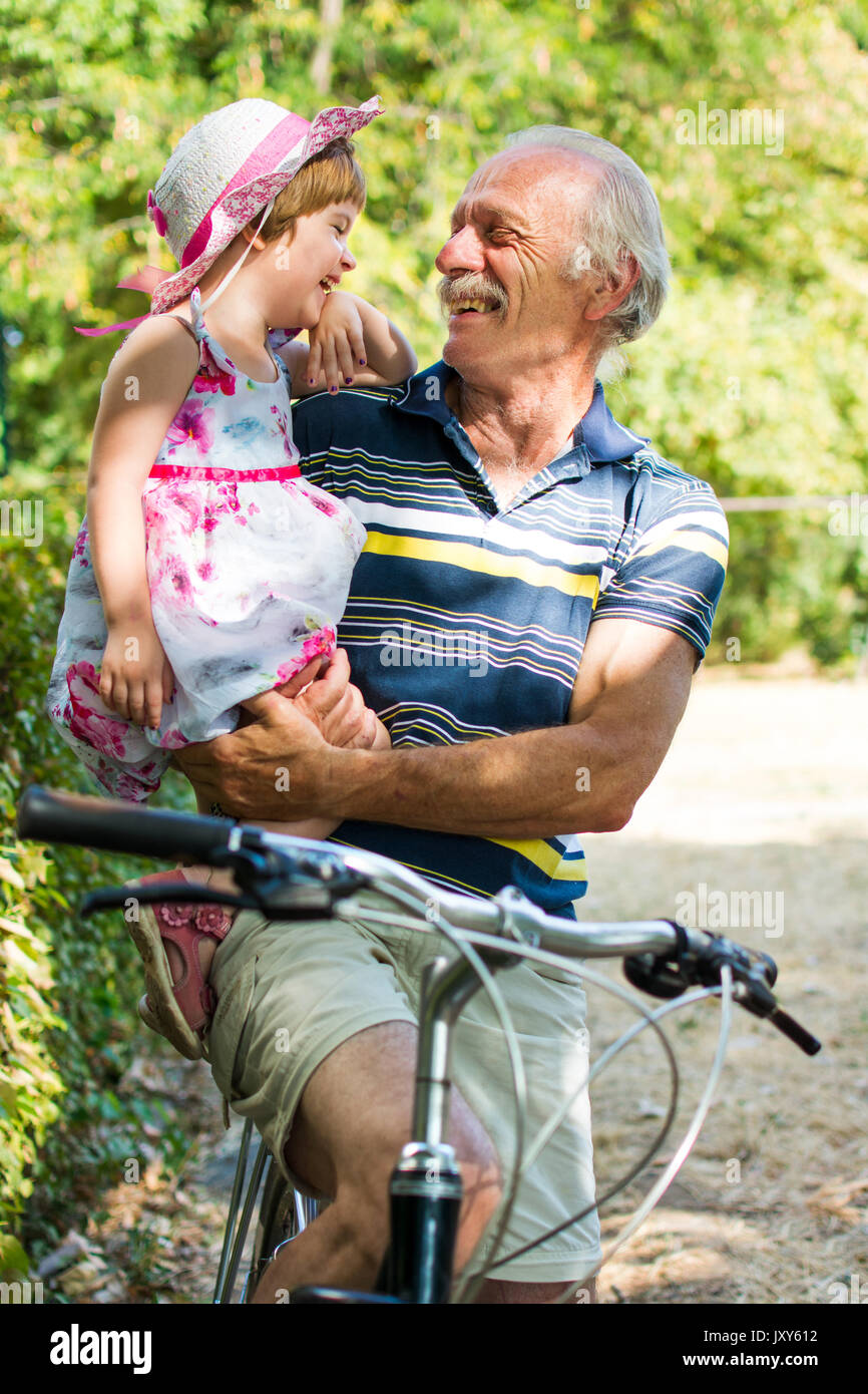 Opa lachend auf dem Fahrrad mit seiner Enkelin Stockfoto