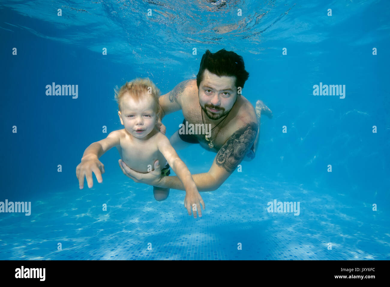 Vater und Sohn spielen unter Wasser im Pool Stockfoto