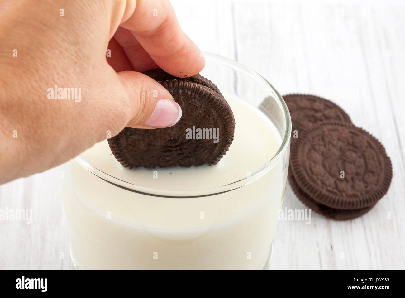 Nahaufnahme einer Frau dunking Schokolade Cookies in Milch Stockfoto