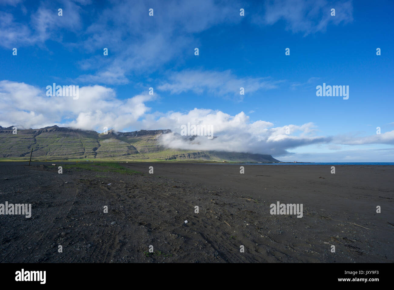 Island - breiten, schwarzen Sandstrand von Eastern Island mit bewölkt Berge Stockfoto
