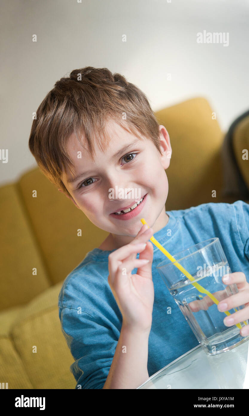 7-jähriger Junge Trinkwasser durch einen Strohhalm Stockfoto