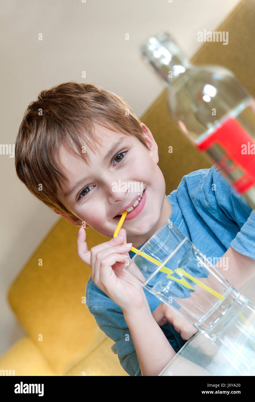 7-jähriger Junge Trinkwasser durch einen Strohhalm Stockfoto