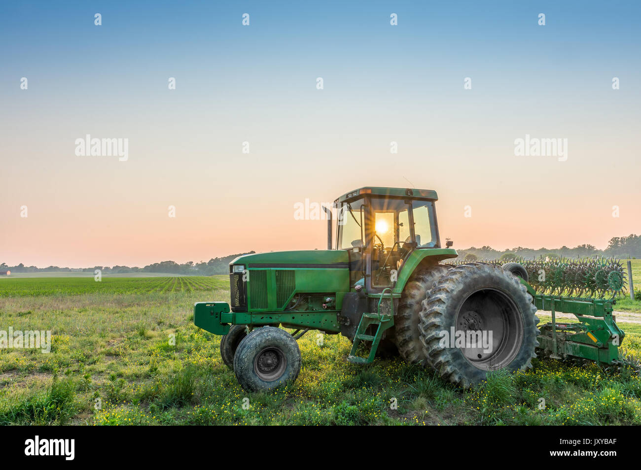 Traktor in einem Feld in einem ländlichen Maryland Farm bei Sonnenuntergang mit Sonnenstrahlen. Stockfoto