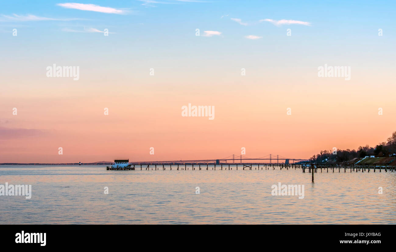 Einen schönen Sonnenuntergang auf der Chesapeake Bay in Maryland mit Bay Bridge, Bootshaus und Leuchtturm Stockfoto