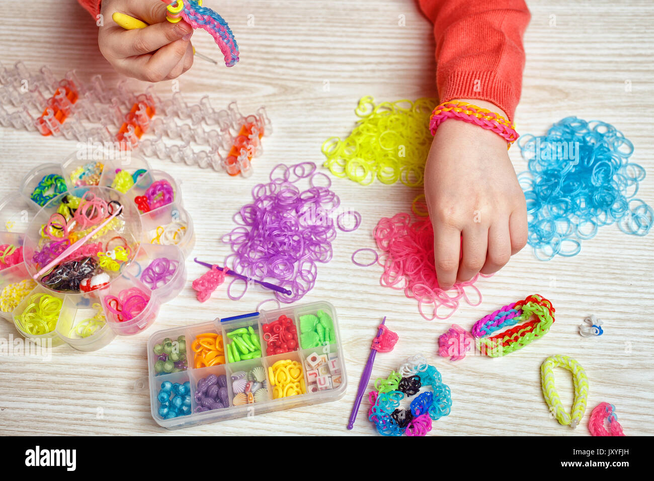 Gummi, Handwerk und Fashion Concept - farbige Gummibänder und Geräte für das Weben von rubber band Bracelet auf Holz- Hintergrund Stockfoto