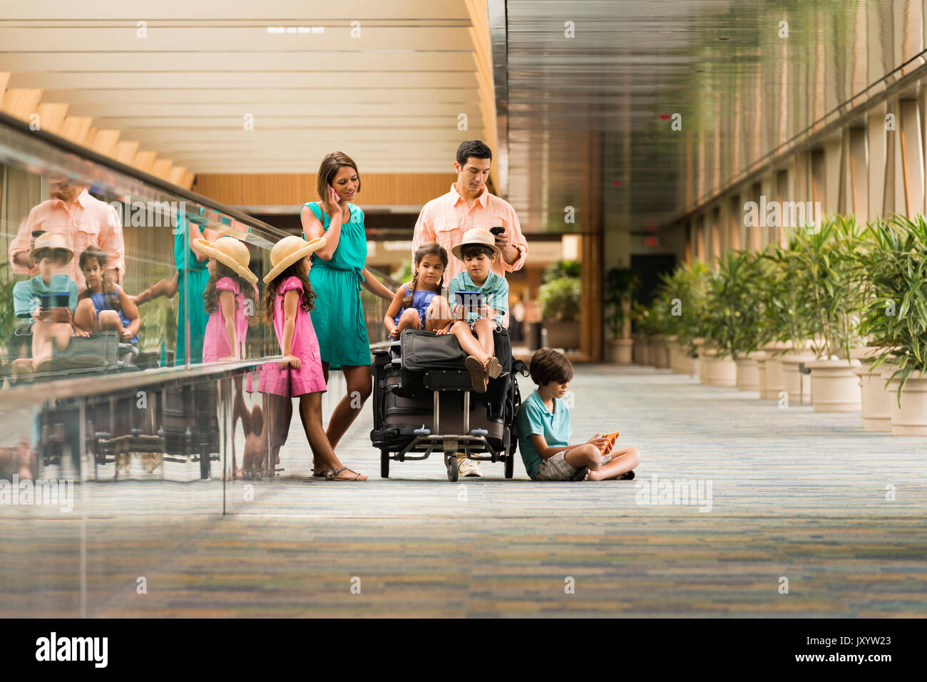 Familie warten im Flughafen über Mobiltelefone Stockfoto