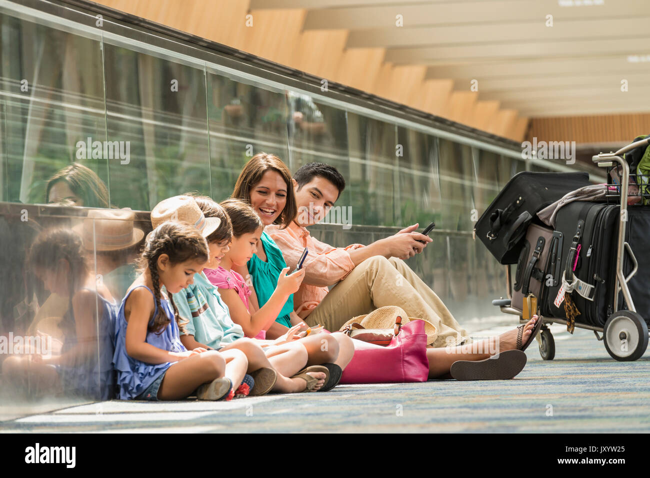 Familie warten auf dem Boden der Flughafen über Mobiltelefone Stockfoto