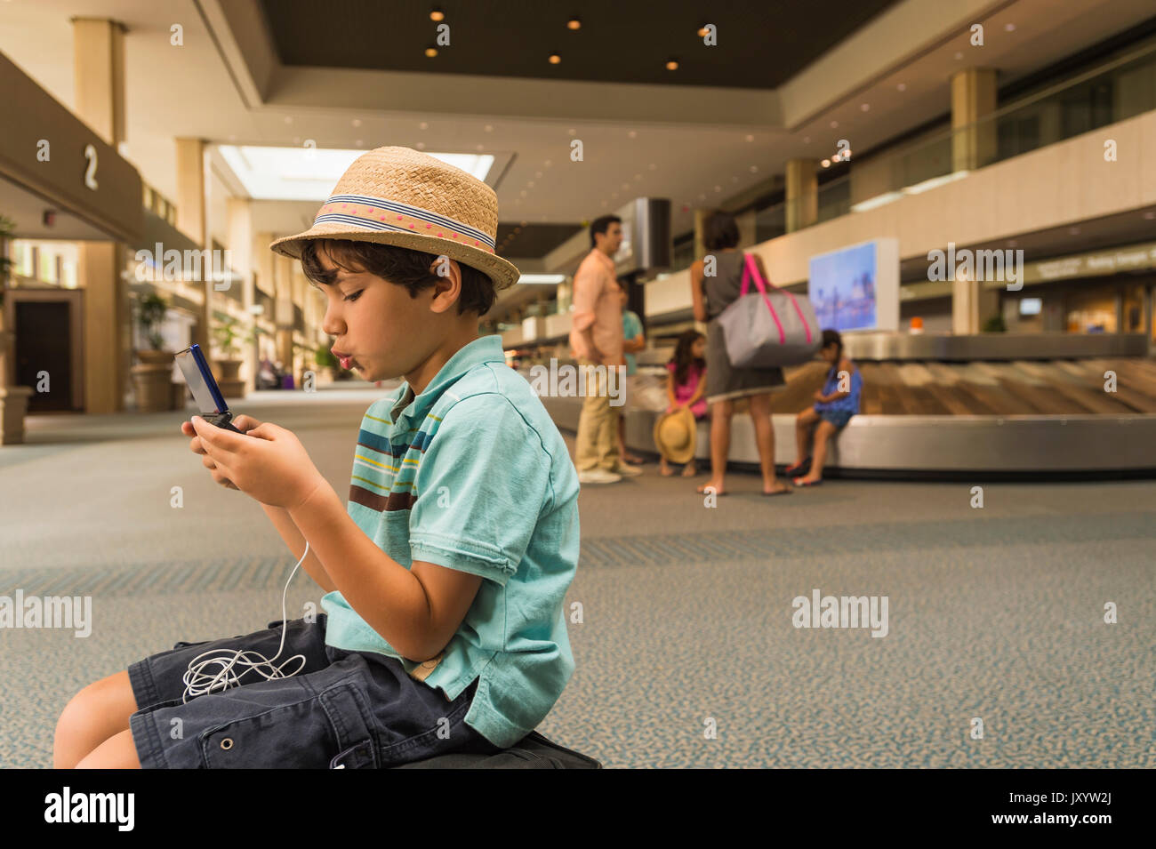 Junge spielt auf Handy im Flughafen Stockfoto