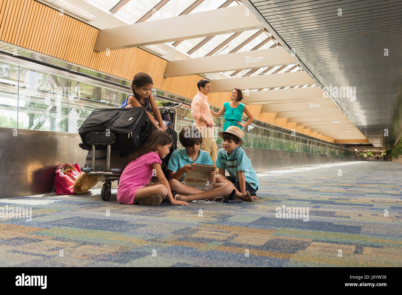 Kinder warten im Flughafen mit der Familie und mit digitalen Tablet Stockfoto