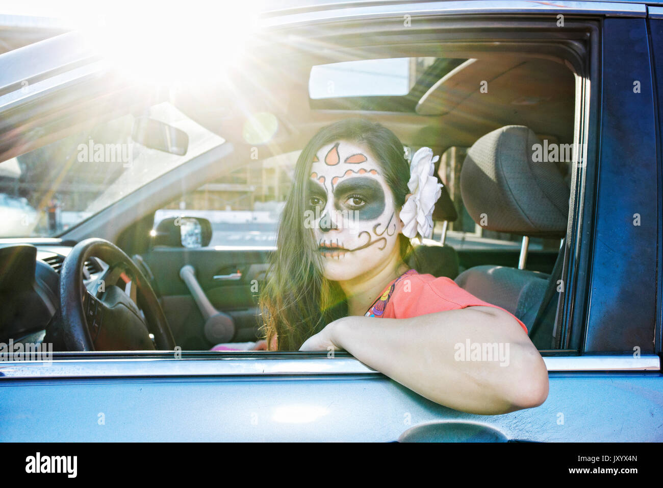Hispanic Frau fahren Auto mit Schädel Gesicht Farbe Stockfoto