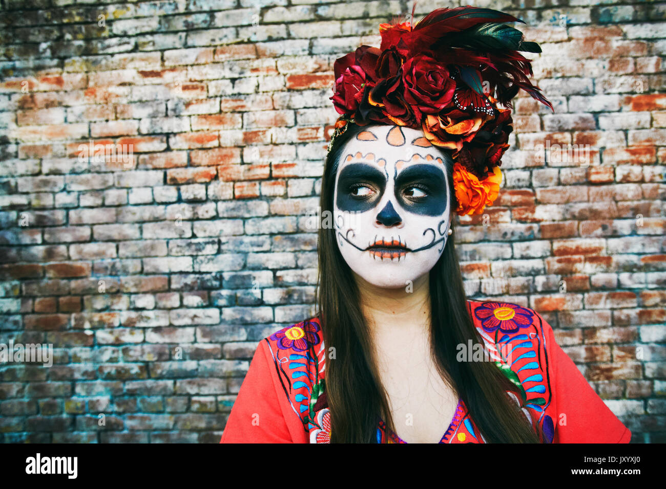 Hispanic Frau in der Nähe von Mauer tragen Schädel Gesicht Farbe Stockfoto