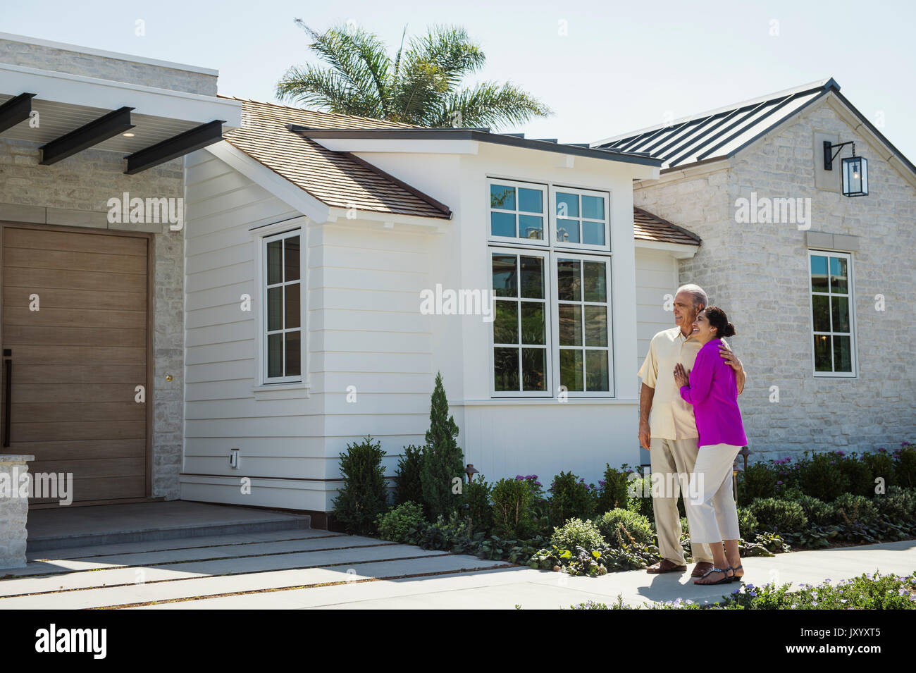 Ältere Paare stehen in der Nähe der Einfahrt des Hauses Stockfoto