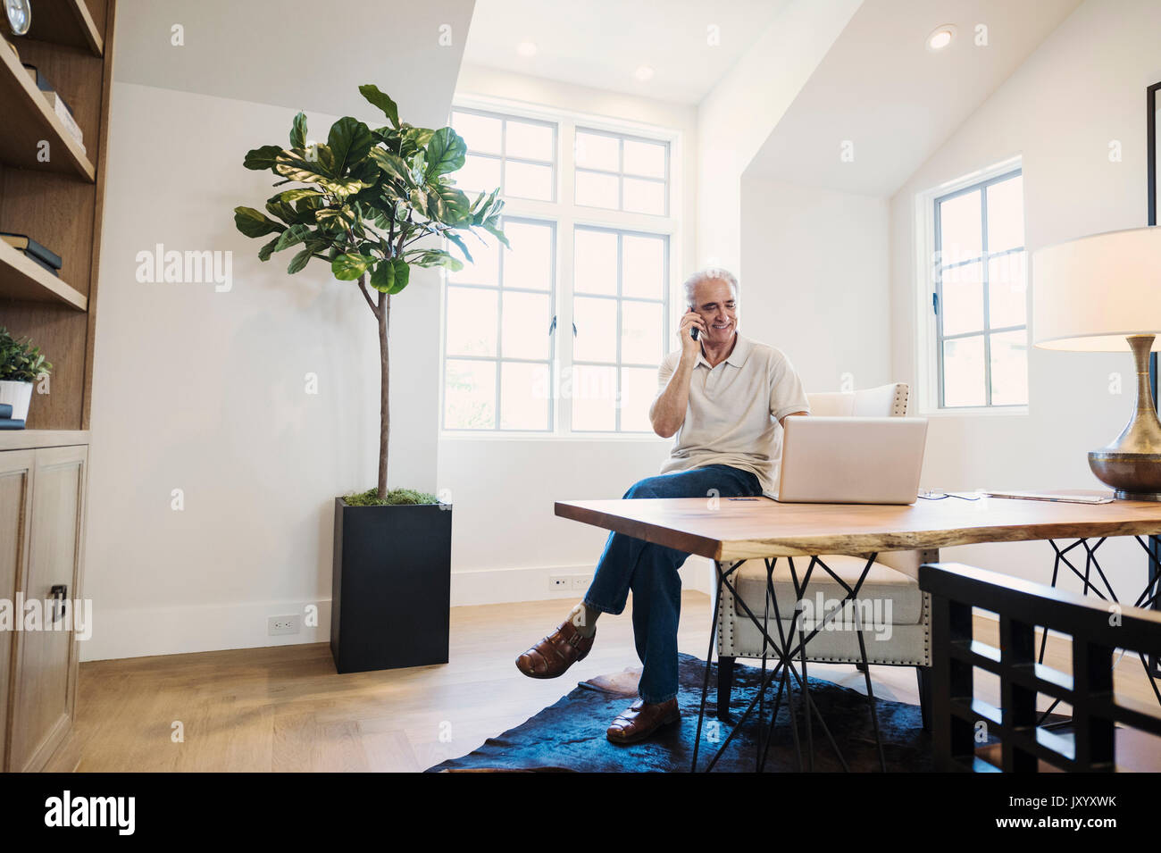 Kaukasische Mann auf Handy im Home Office Stockfoto