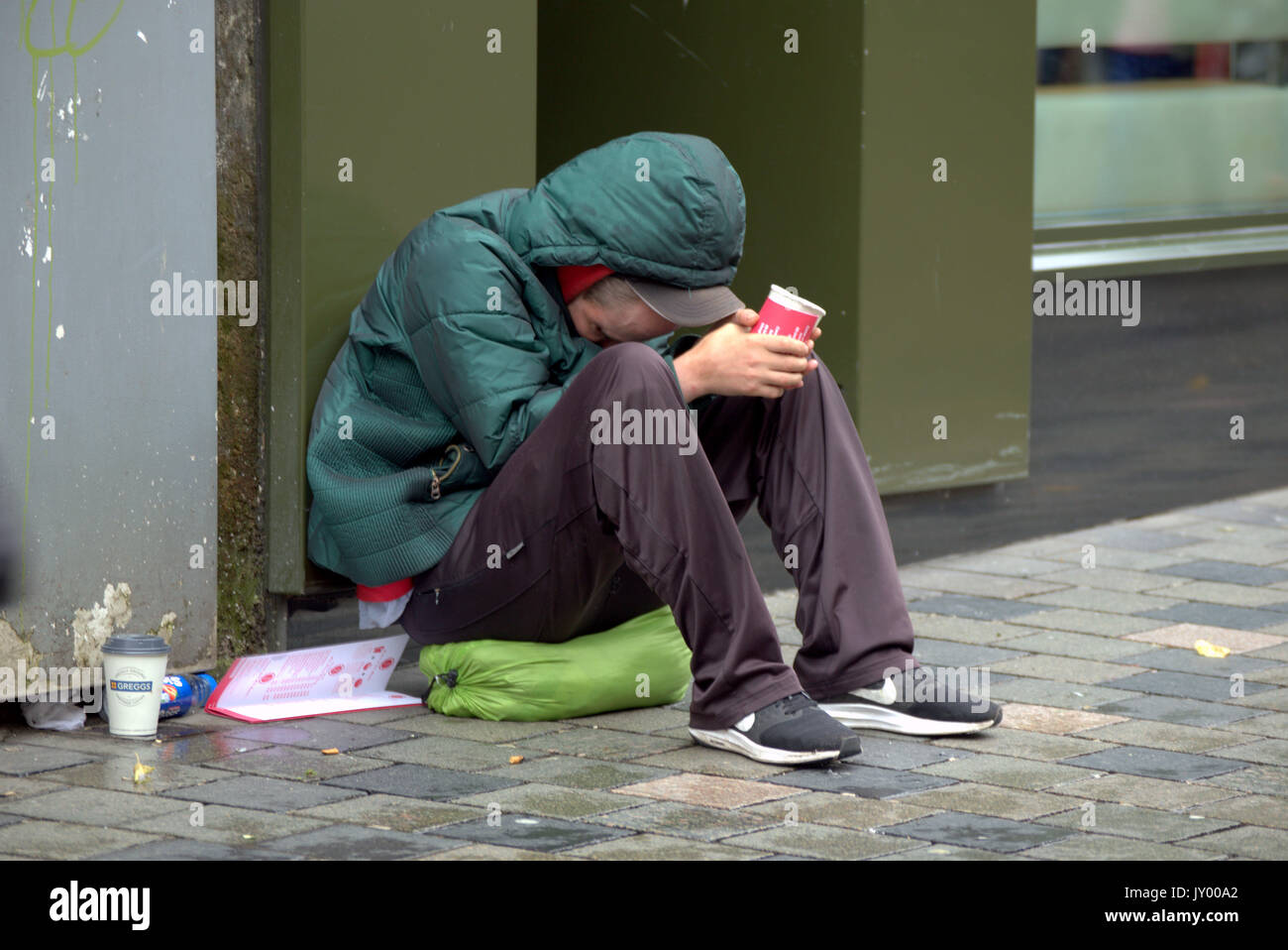 Mann arbeitslos Obdachlose Betteln auf der Straße mit Tasse Menschen zu Fuß durch Betteln Stockfoto