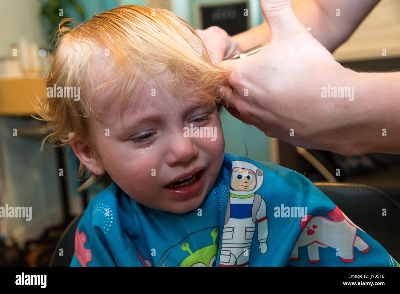Kaukasische Toddler boy sitzt und weint, während Er sich die Haare schneiden. Stockfoto