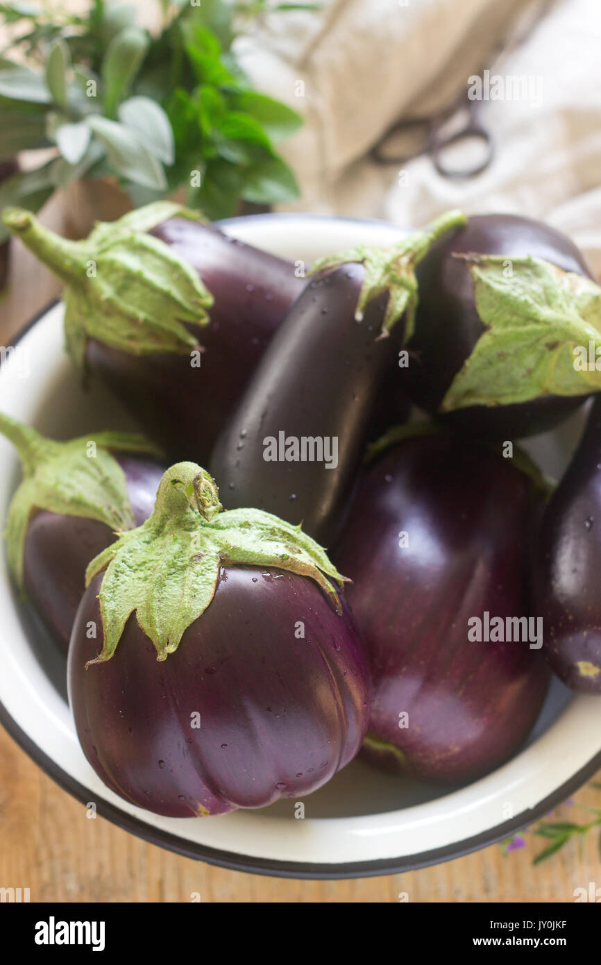 Auberginen in einer Schüssel auf einem Holztisch. Vertikale. Selektive konzentrieren. Stockfoto