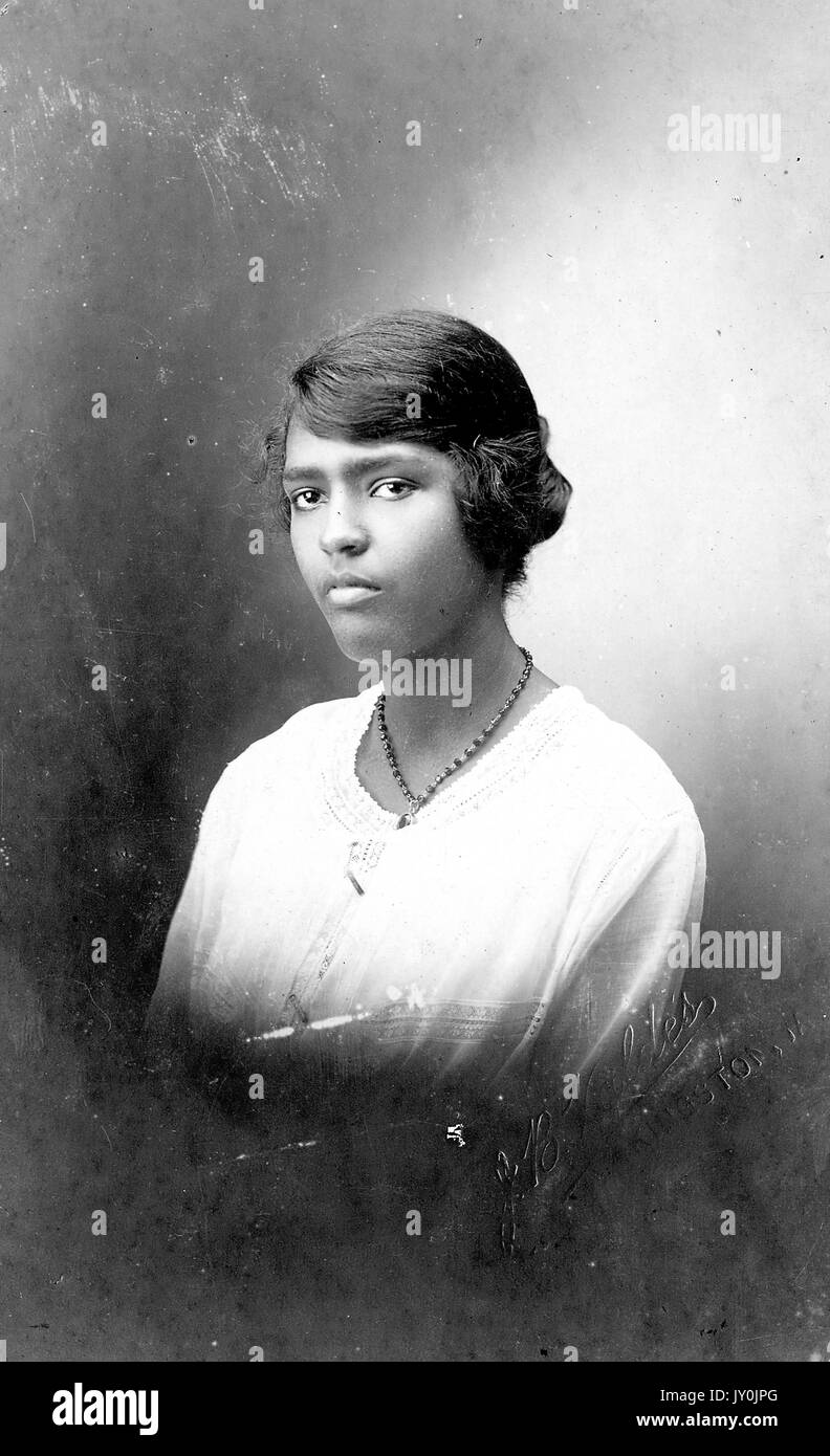 Porträt der oberen Hälfte einer jungen afroamerikanischen Frau, trägt sie ein helles Oberteil und eine dunkle Halskette, 1915. Stockfoto