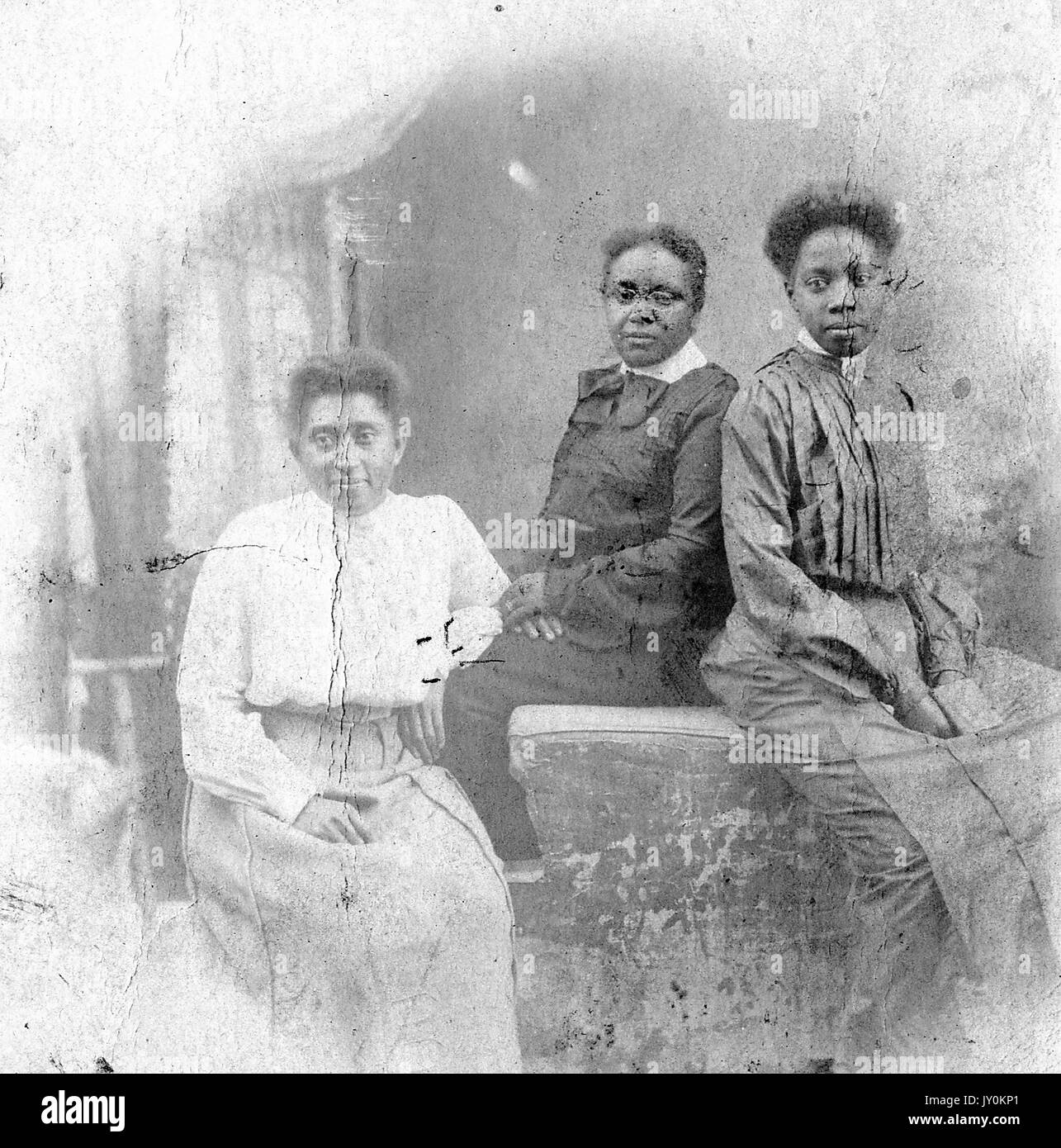 Drei Viertel lang sitzende Porträt von drei reifen afroamerikanischen Frauen, eine in hellem Kleid, zwei in dunklen Kleidern, auf Sofas sitzend, neutrale Ausdrücke, 1915. Stockfoto