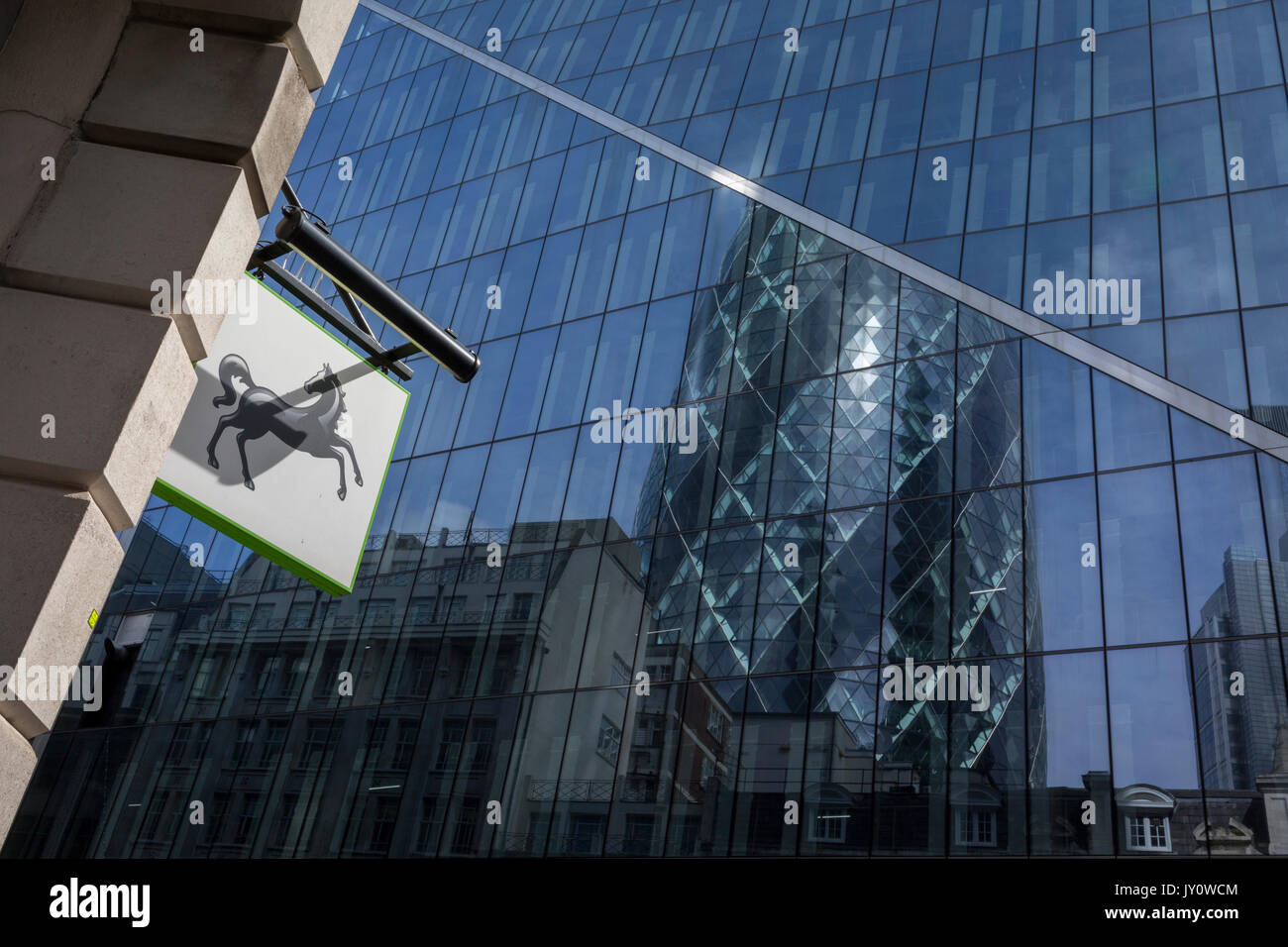 Die Marke der Lloyds Bank, ein schwarzes Pferd, und Hintergrund Banken und Versicherungen Zentrale einschließlich der Swiss Re Gebäude (aka The Gherkin) im ältesten Stadtteil der Hauptstadt, der Square Mile, am 14. August 2017, in der City von London, England. Stockfoto