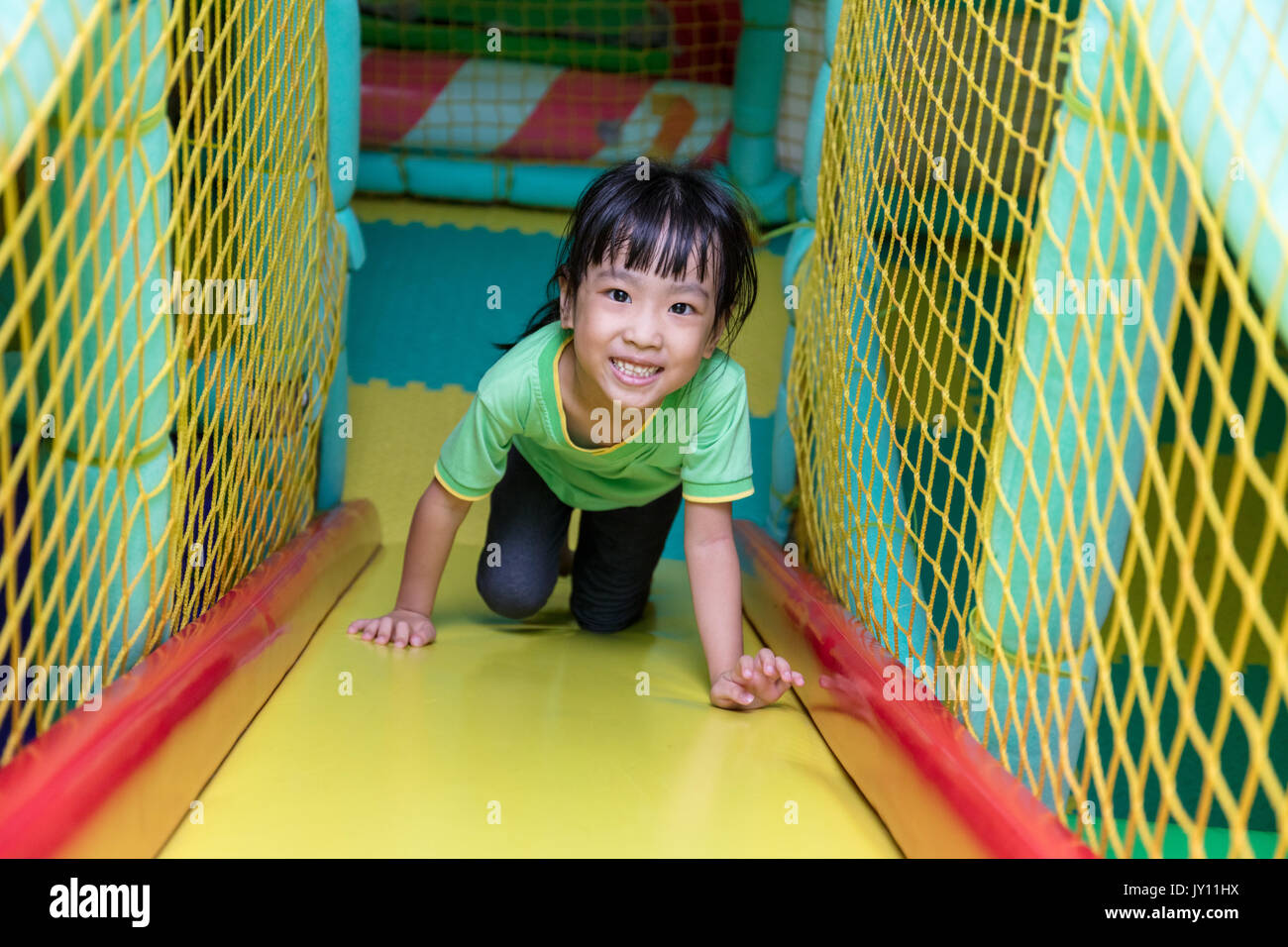 Asiatische chinesische Mädchen Dia an Indoor Spielplatz alleine spielen Stockfoto