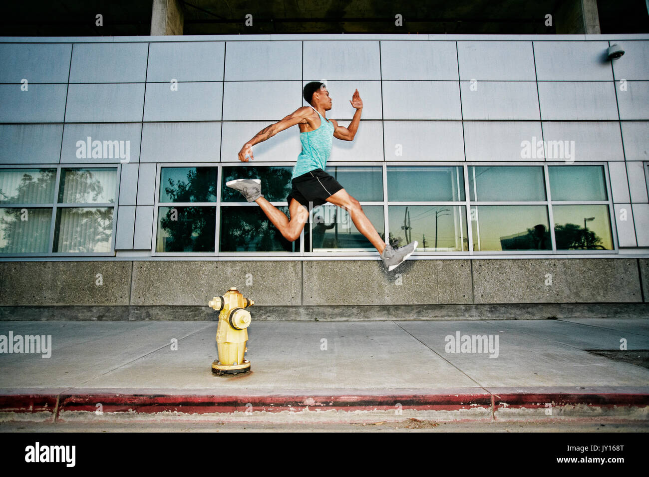 Schwarzer Mann laufen und springen über Hydranten Stockfoto