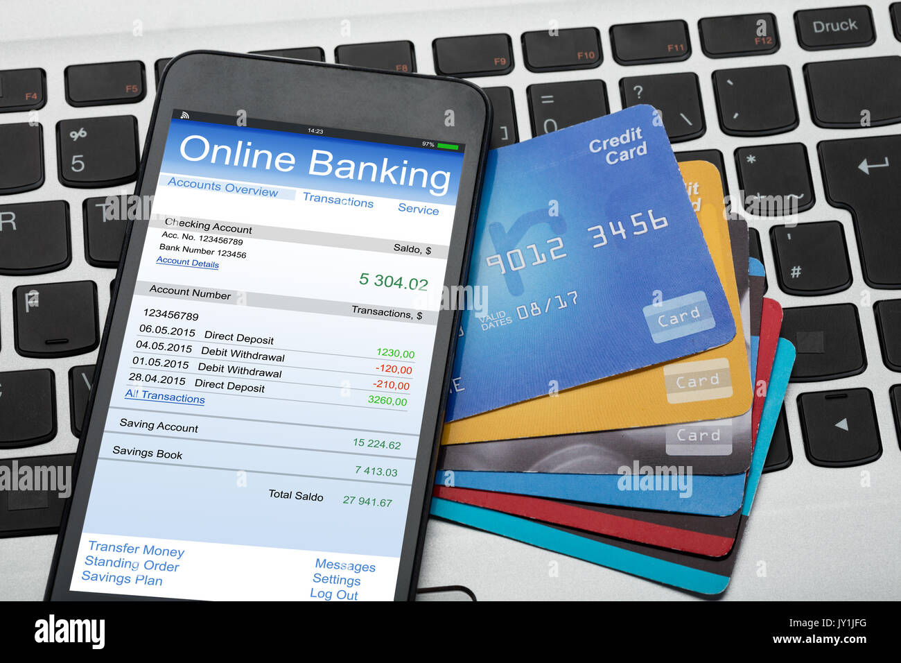 Hohe Betrachtungswinkel von Mobilephone mit Online Banking und Kreditkarten auf Laptop Tastatur Stockfoto