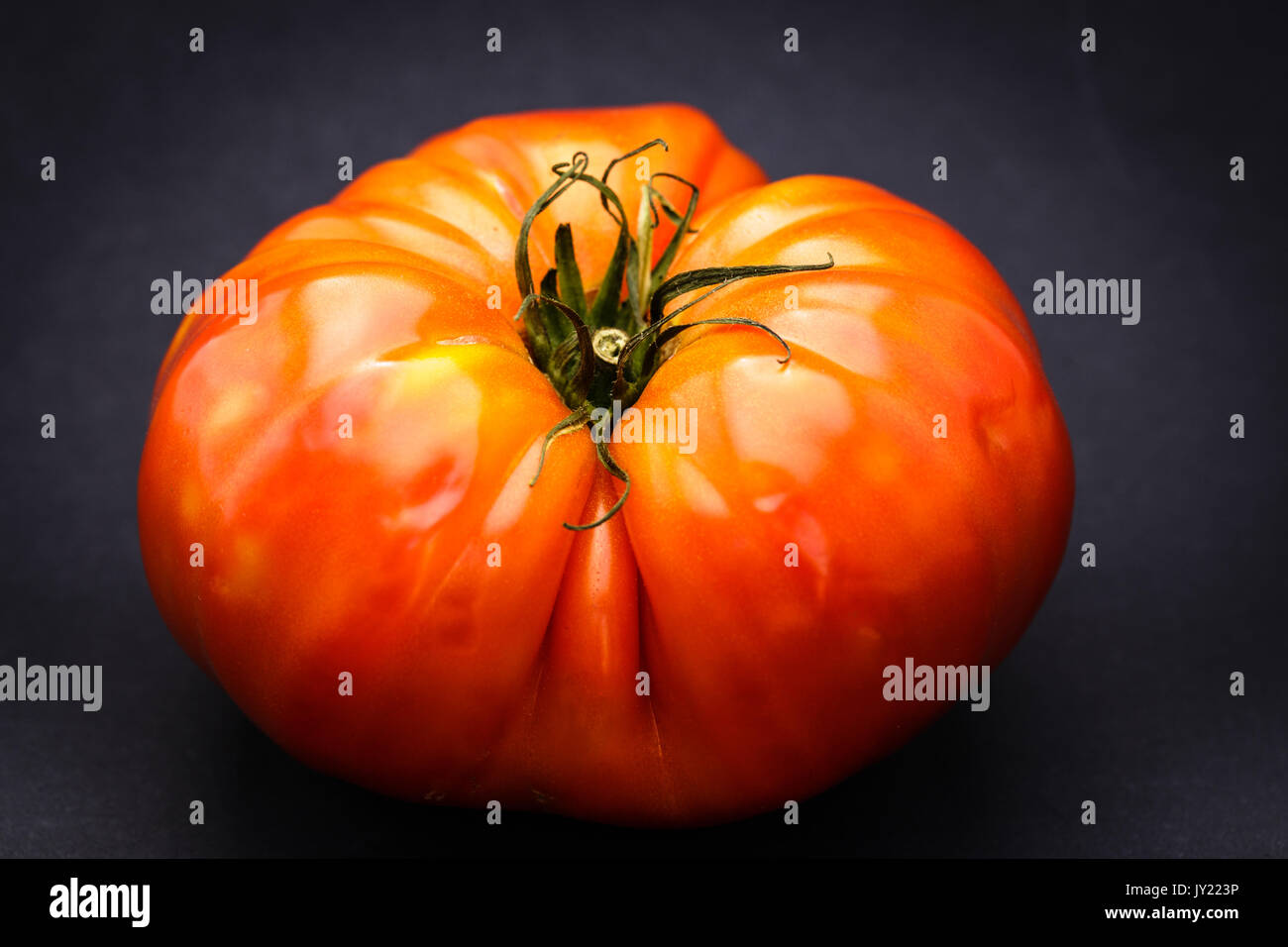 Reif Heirloom Tomaten isoliert auf schwarzem Hintergrund. Die Tomate ist rot und bereit, gegessen zu werden. Stockfoto