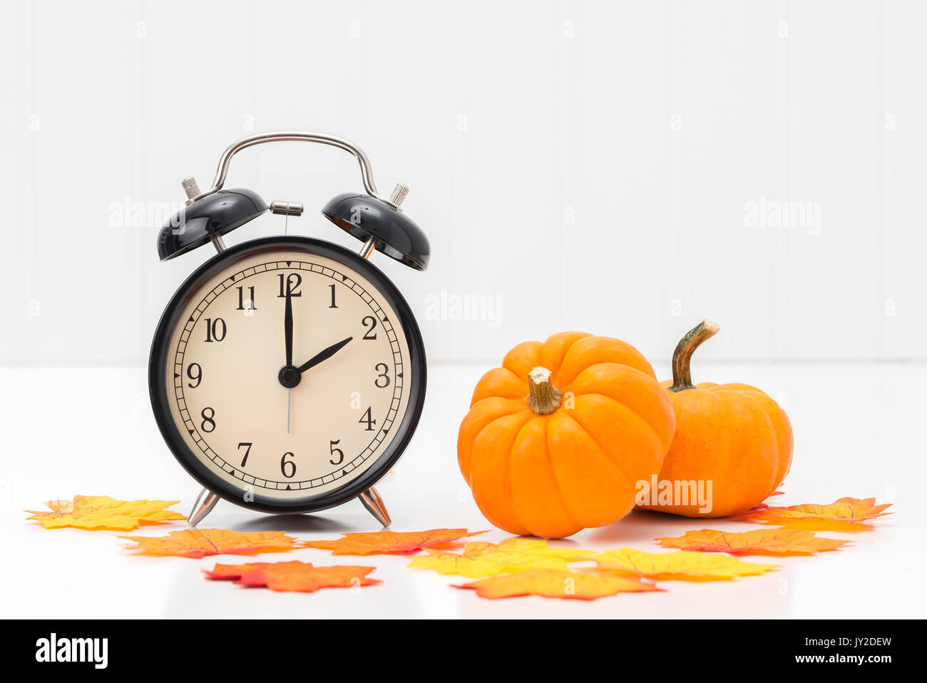 Wecker mit bunten Herbstlaub und Kürbisse das Konzept der Sommerzeit zu vertreten. Stockfoto