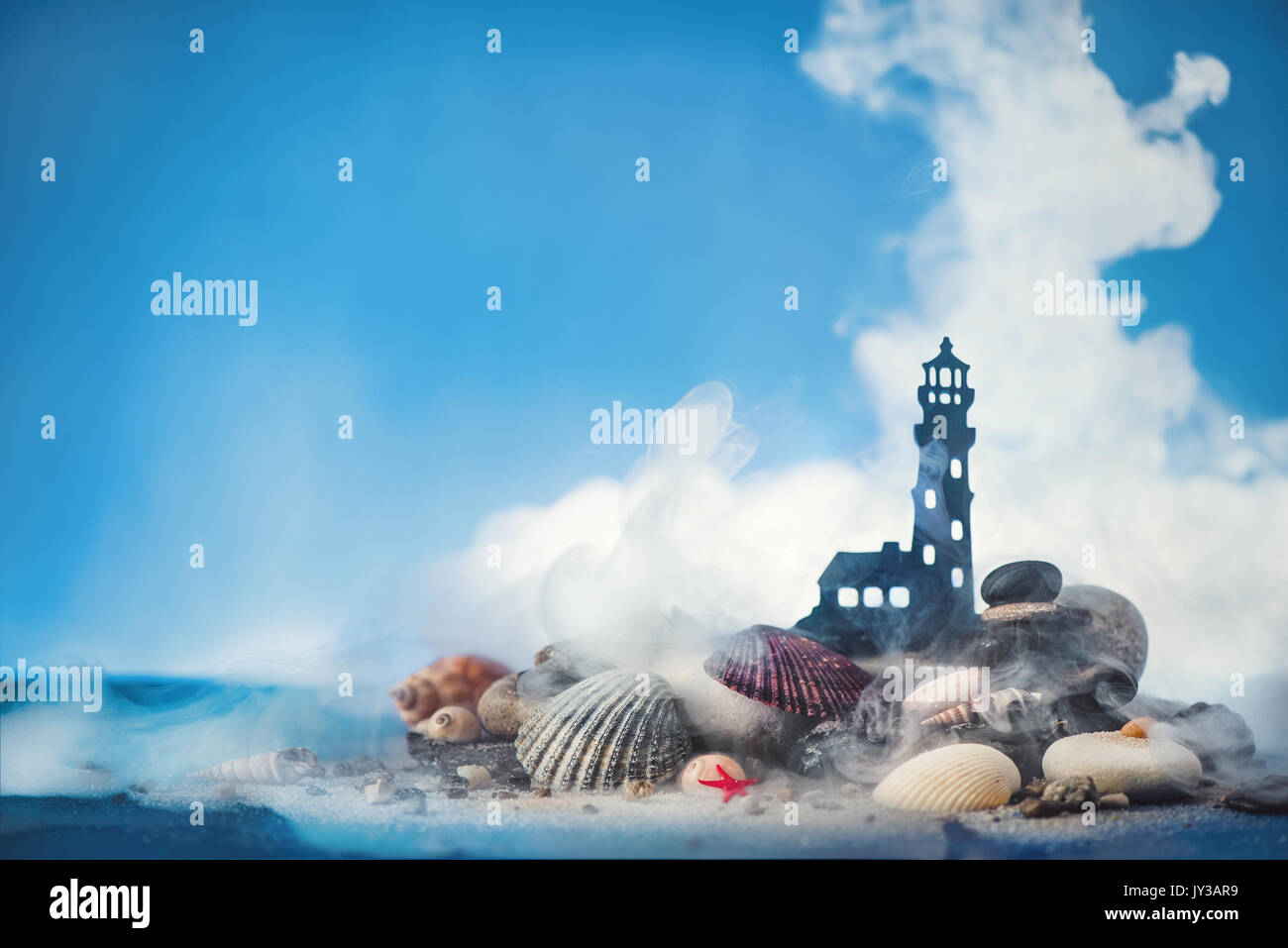 Thema See konzeptionelle Shot mit kleinen Leuchtturm auf einem Haufen Sand und Muscheln auf blauem Hintergrund. Kopieren Sie Platz. Stockfoto