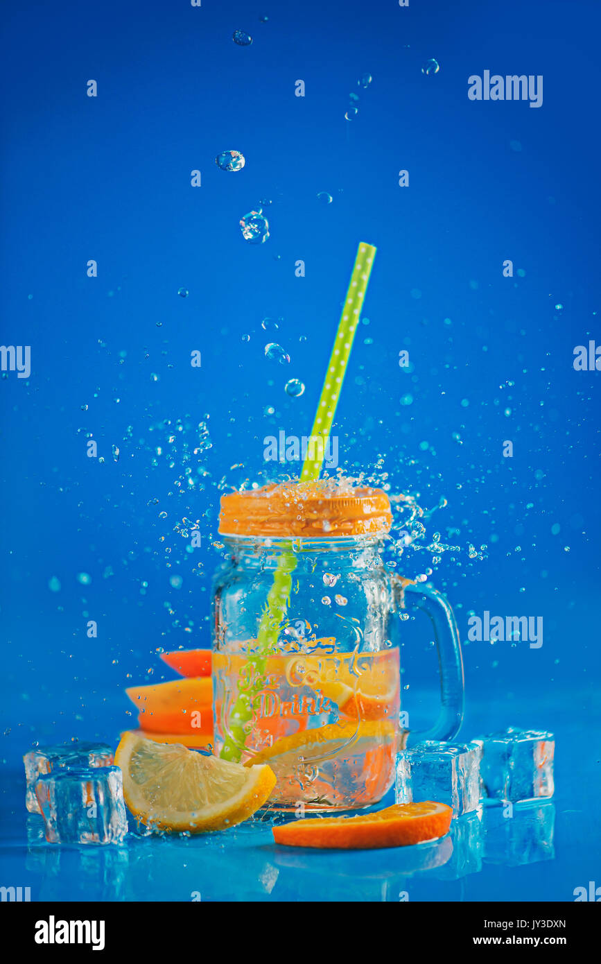 Glas Glas mit Limonade auf einem blauen Hintergrund mit Wasser spalsch Stockfoto