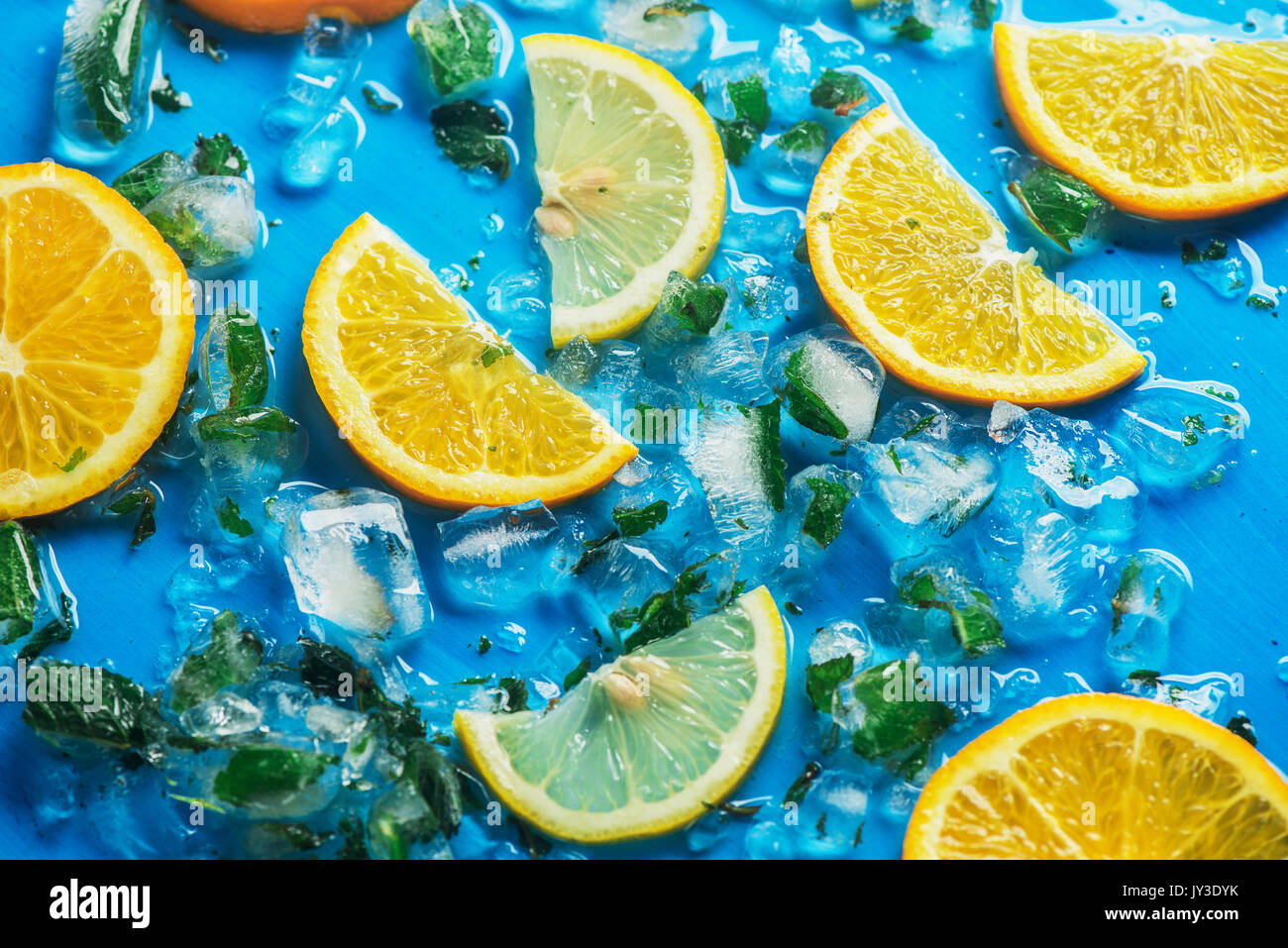 Close-up von geschnittenen Orangen und Zitronen auf blauem Hintergrund mit Eiswürfel Stockfoto