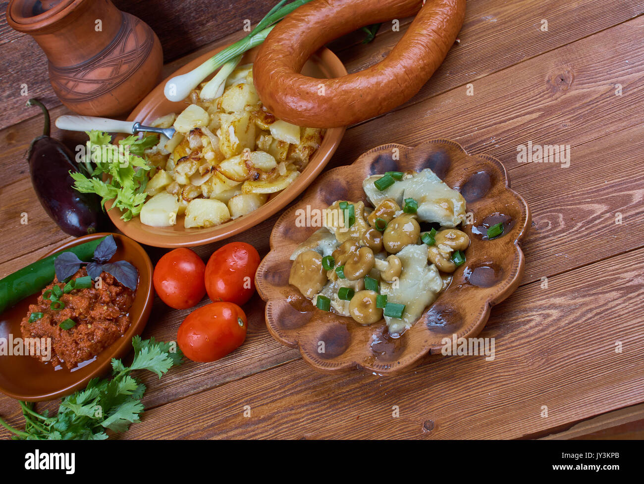 Russischer Sommer Abendessen, Essen im Sortiment: Bratkartoffeln, geräucherte Wurst, Auberginen Kaviar, Gesalzene Pilze. Stockfoto