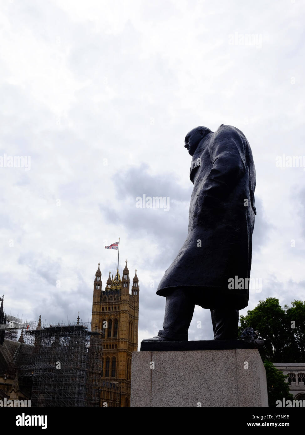 Die Statue von Winston Churchill in Parliament Square, London, über die Häuser des Parlaments als Big Ben Stiller geht. Stockfoto
