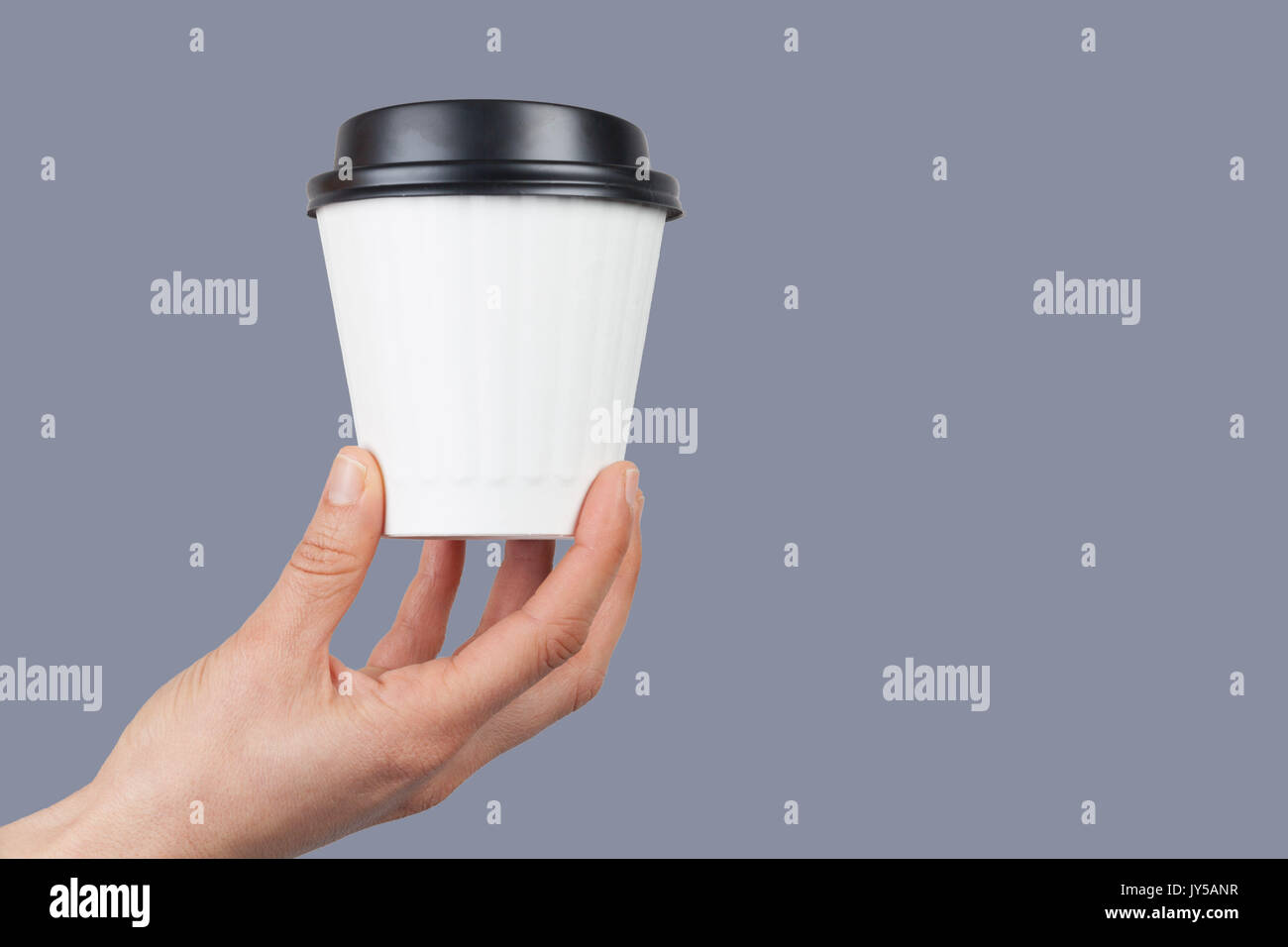 Weibliche Hand, die eine verfügbare weiß Kaffeetasse auf grauem Hintergrund mit Kopie Raum isoliert Stockfoto